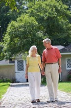 Senior couple walking in back yard.