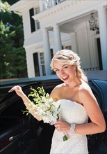Smiling bride standing near limousine.