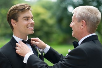 Father adjusting groom's bow tie.