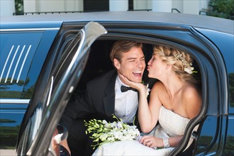Newly wed couple sitting in limousine.