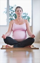 Pregnant woman sitting in lotus position.