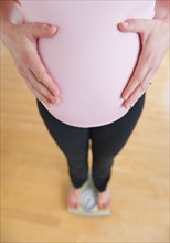 Pregnant woman weighing herself.