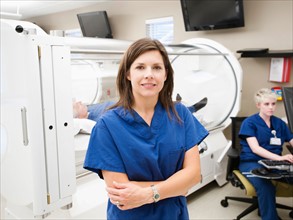 Young female nurse standing in front of CAT scanner.