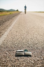 Man walking away leaving his wallet behind on empty road .