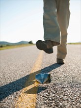 Man kicking tin can on otherwise empty road.