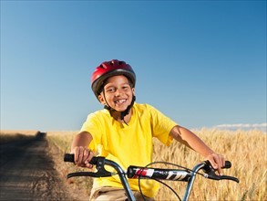 Boy (8-9) cycling along dirt road.