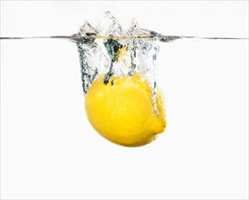 Studio shot of lemon splashing into water.