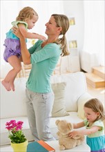 Mother playing with daughters (2-3) in living room.