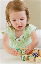 Girl (2-3) playing with letter blocks.