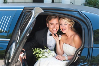 Portrait of newly wed couple sitting in limousine.