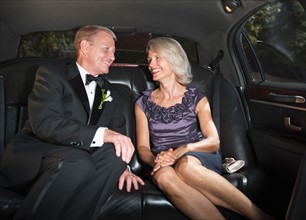 Parents of bride in limousine looking at each other.