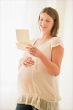 Pregnant woman reading letter.