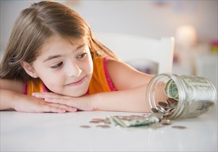 Girl ( 6-7) looking at savings in jar. Photo : Jamie Grill