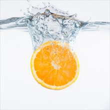 Orange splashing into water, studio shot. Photo: Daniel Grill