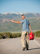 USA, Utah, Kanosh, Mid adult man carrying empty canister attempting to stop vehicles for help.