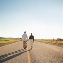 Mid adult couple walking along empty road . Photo: Erik Isakson