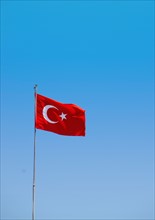 Turkey, Turkish flag against blue sky. Photo: Tetra Images