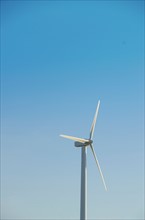 Turkey, Cesme, wind turbine against blue sky. Photo : Tetra Images
