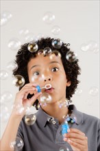 Studio portrait of boy (8-9) blowing bubbles. Photo: Rob Lewine