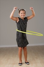 Studio portrait of girl (8-9) spinning plastic hoop. Photo : Rob Lewine