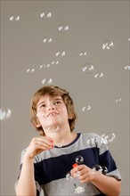 Studio shot of boy (8-9) blowing bubbles. Photo : Rob Lewine