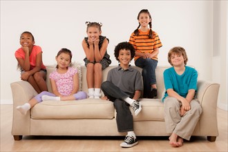 Studio portrait of six children (8-9) sitting on sofa. Photo: Rob Lewine