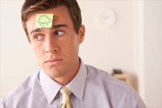 Businessman with adhesive note attached on forehead. Photo : Rob Lewine