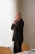 Thoughtful businessman standing in board room. Photo : Rob Lewine