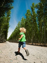 Boy (2-3) running up country road.