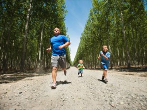 Father with sons (2-9) running down country road. Photo: Erik Isakson
