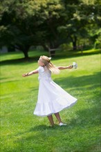 Flower girl (10-11) dancing on grass.