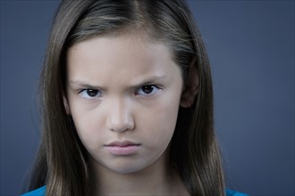 Portrait of girl (8-9) looking angry, studio shot. Photo : Rob Lewine
