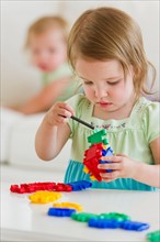 Girl (2-3) playing with colorful toys.