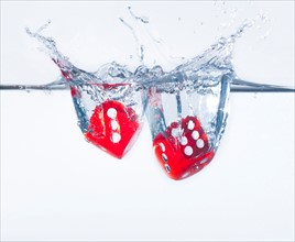 Two dices splashing into water, studio shot. Photo : Daniel Grill