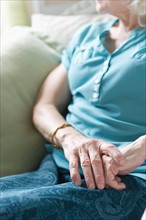 Senior woman sitting in chair, close-up of hands.