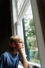 Boy (10-11) looking out window.