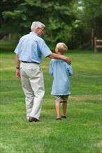Grandfather and grandson (10-11) walking in park.