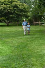 Grandfather and grandson (10-11) walking in park.