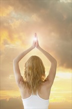 Woman saluting sun in yoga gesture.