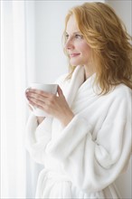 Woman in bathrobe drinking coffee.