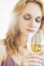Portrait of young woman smelling wine, studio shot.