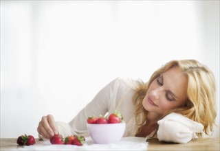 Woman eating strawberries, studio shot.