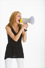 Woman shouting through bullhorn, studio shot.