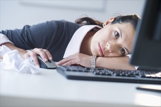 Businesswoman in front of computer, looking tired.