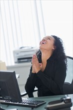 Business woman using computer and laughing.