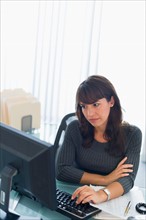 Business woman using computer, looking tired.