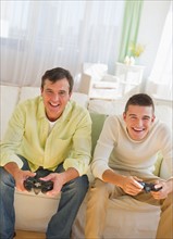 Father and son (16-17) playing video game.