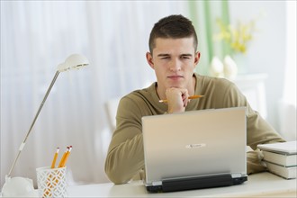 Boy (16-17) using laptop.