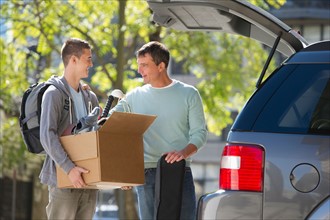 Father helping teenage son (16-17) packing to college.