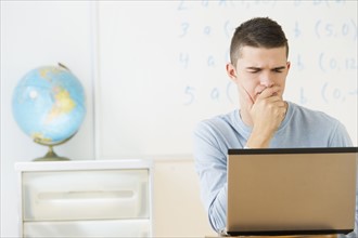 Teenage (16-17) student using laptop.